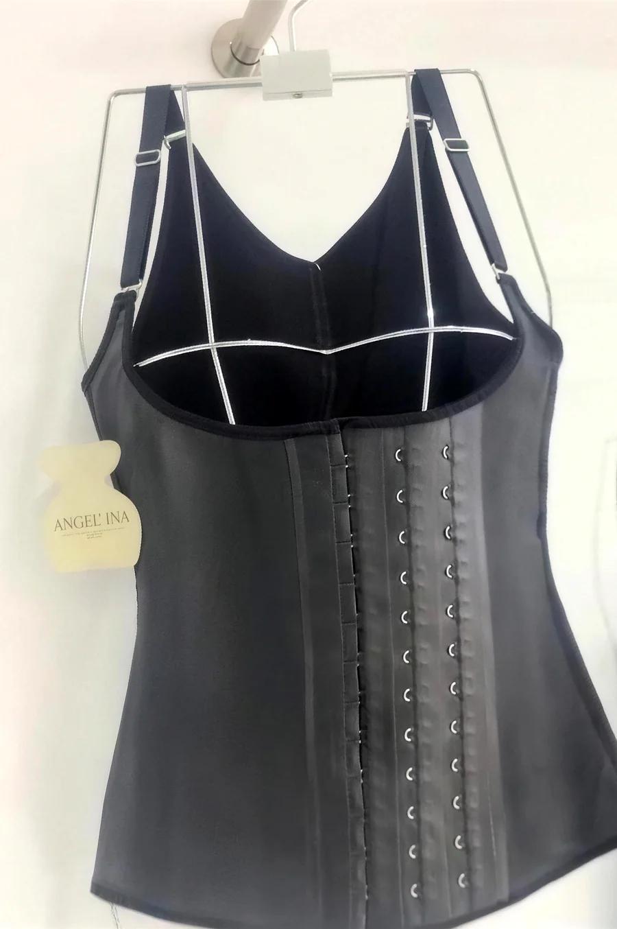 Le gilet en latex noir sur un buste à la boutique, trois colonnes de crochets, étiquette Angel’ina